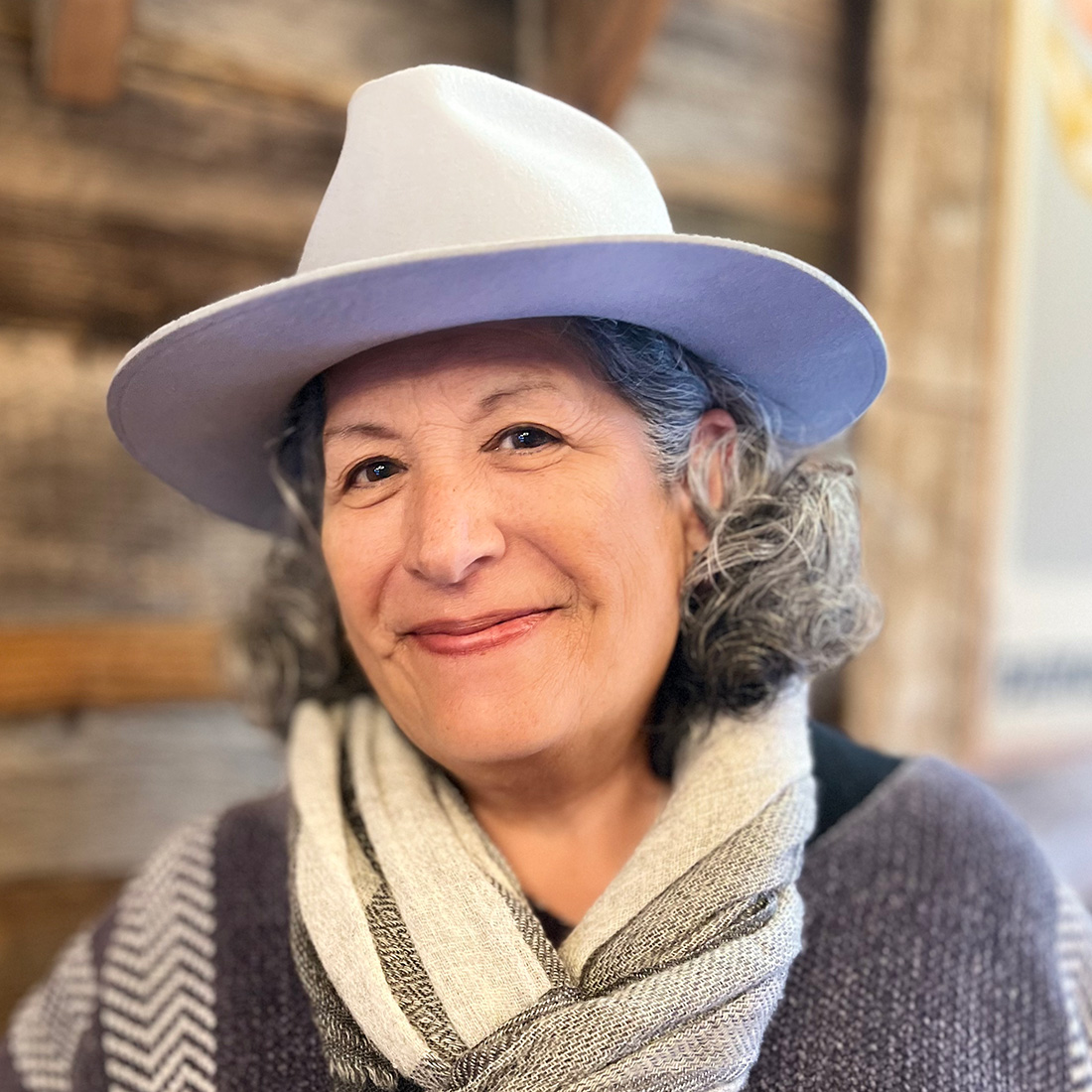 casual photo of jeanne wearing a fedora, wool poncho, and scarf