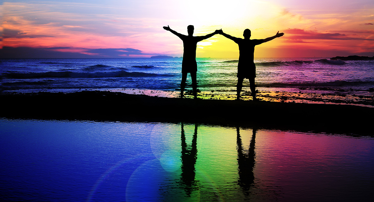 laura cartwright she/her has shoulder length blonde hair and is wearing a black turtleneck. she is standing on the beach with a sunset in the background