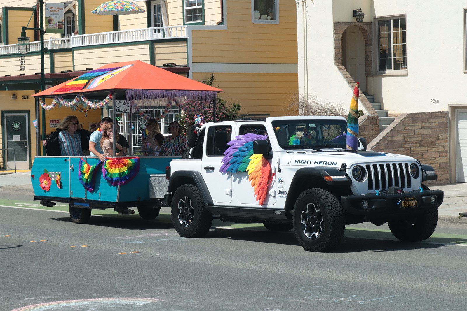 white jeep with pride colored wings towing the coastpride trailer